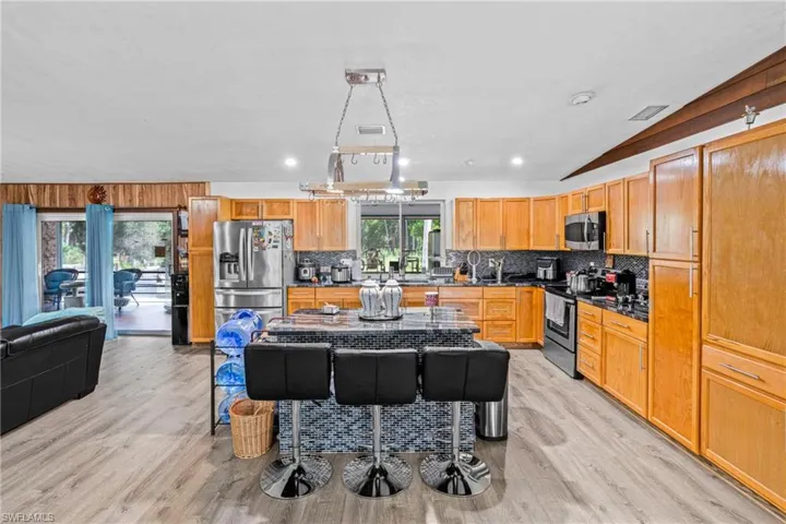 Kitchen with light wood-style flooring, appliances with stainless steel finishes, recessed lighting, backsplash, and brown cabinets