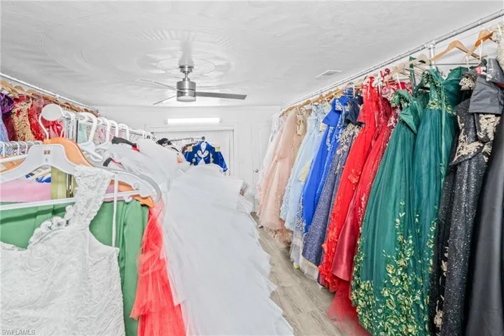 Walk in closet with wood finished floors and a ceiling fan
