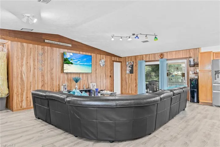 Living area with wood walls, vaulted ceiling, and light wood-style flooring