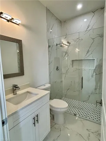 Bathroom featuring vanity, toilet, and a shower with shower door