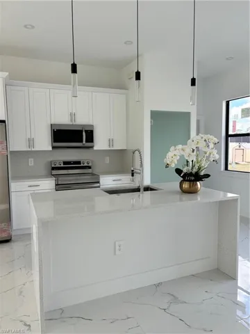 Kitchen featuring pendant lighting, white cabinetry, and range