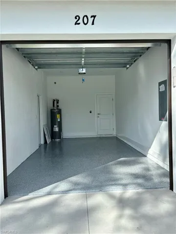 Garage with water heater, a garage door opener, and electric panel