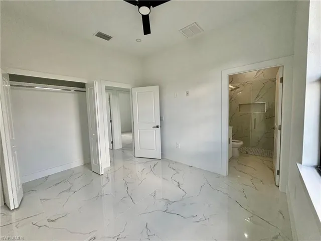 Unfurnished bedroom with ceiling fan, ensuite bathroom, and a closet