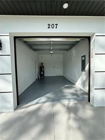 Garage featuring water heater, a garage door opener, and electric panel