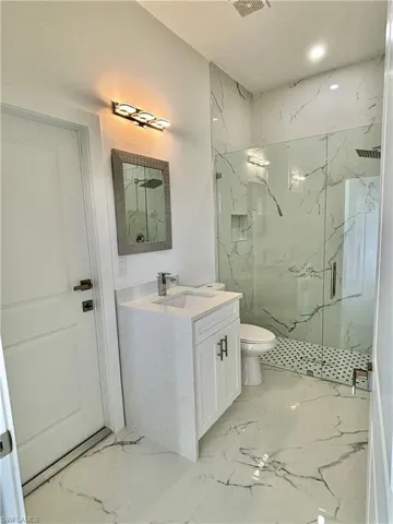 Bathroom with vanity, an enclosed shower, and toilet