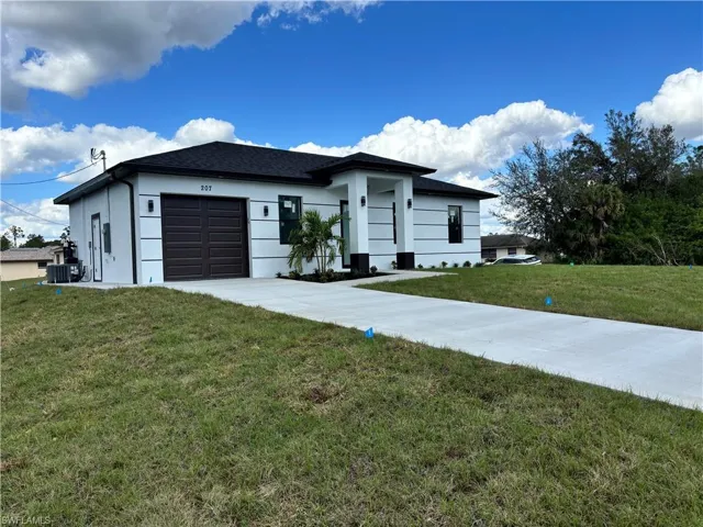View of front of house with a garage, a front yard, and central AC unit