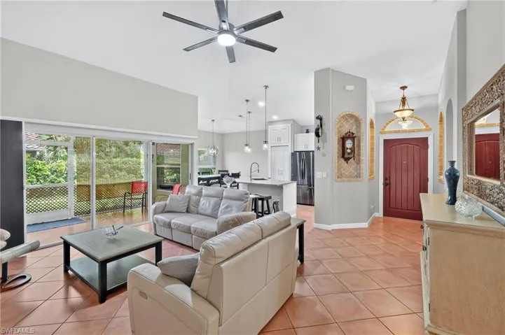 Expansive tile flooring, vaulted ceilings, and a large sliding glass door opening to a screened enclosure