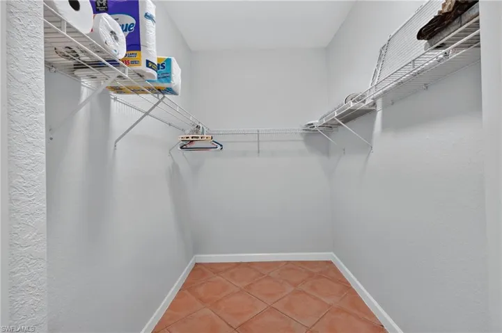 Master bedroom Walk-in closet featuring wire shelving, hanging rods, and terra cotta tile flooring