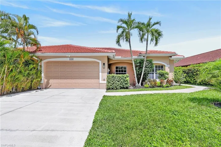 Paved driveway, terracotta tile roof, integrated garage, mature palm trees, and front landscaping