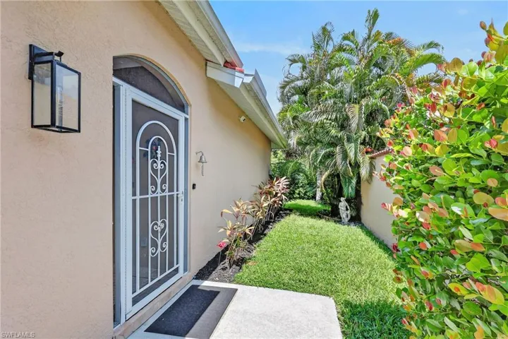 Arched entry with decorative security door, featuring an exterior lantern light fixture and bell