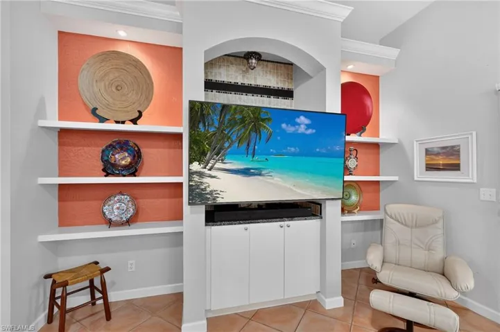 Built-in media center with white cabinetry, integrated shelving, arched alcove, and recessed lighting