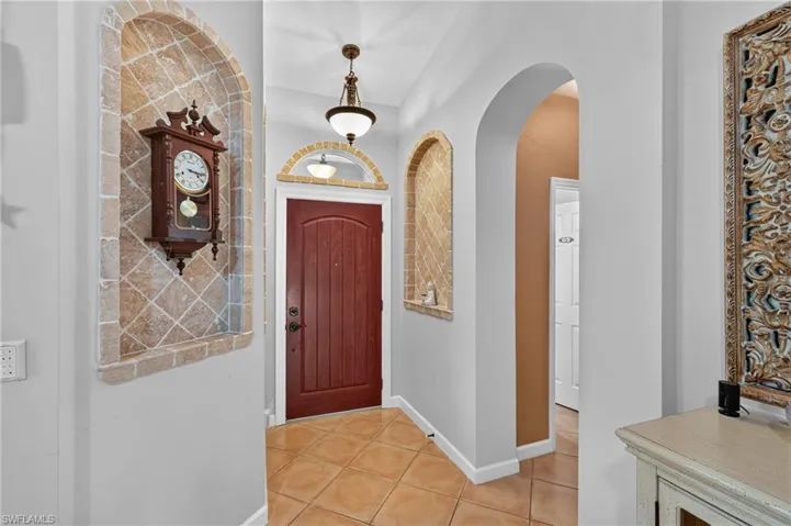 Arched wall niches with decorative tile, solid - Beautiful wood entry door, and tiled flooring