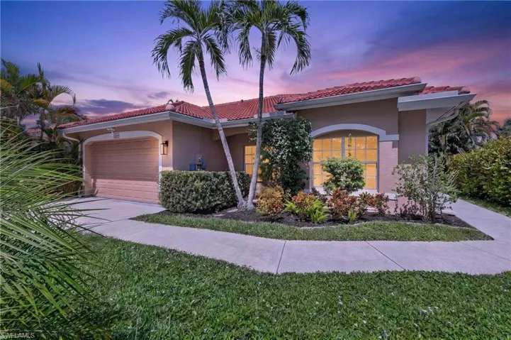 Stucco exterior with a red tile roof, arched entryway, and an attached garage