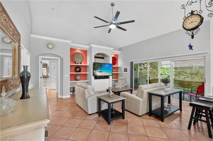 Vaulted ceiling with an integrated ceiling fan, ceramic tile flooring, built-in shelving, sliding glass doors, and recessed lighting