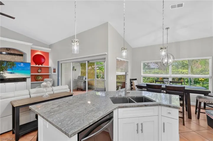 Kitchen island featuring a dual basin sink and stone countertop