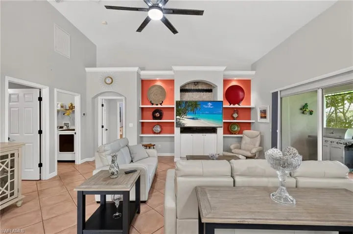 Vaulted ceilings with a ceiling fan, a built-in media center with shelving, and sliding glass doors to the exterior