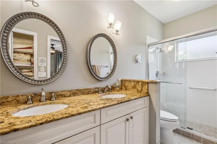 Bathroom with tile patterned floors, a walk in shower, toilet with bidet, and double sink vanity