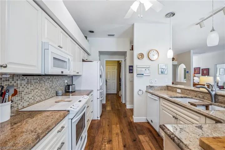 Kitchen featuring decorative light fixtures, ceiling fan, white appliances and sink