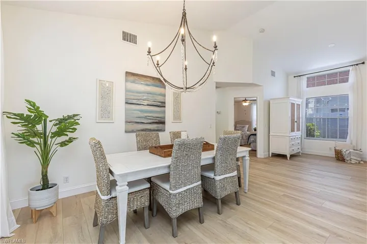 Dining space with ceiling fan, high vaulted ceiling, and light hardwood / wood-style floors