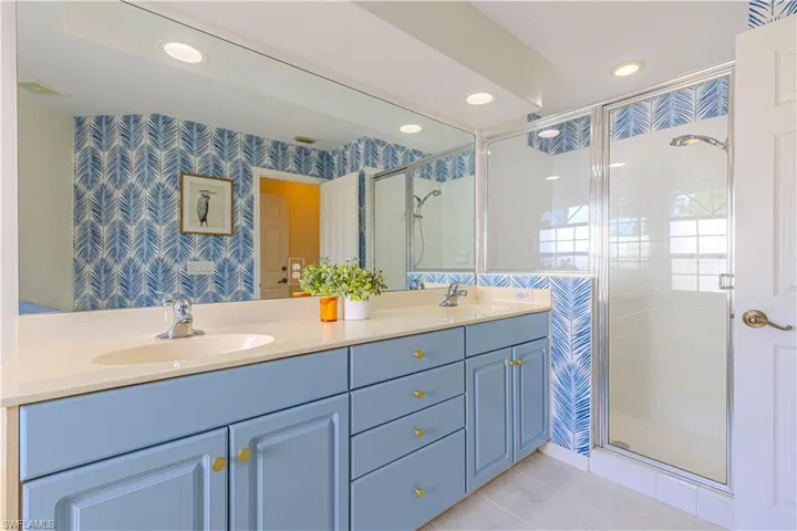 Bathroom featuring a shower with glass door, vanity, and tile patterned floors.