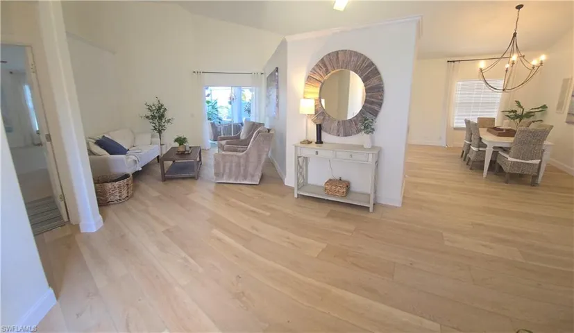 Living area featuring light wood finished floors, baseboards, and a chandelier