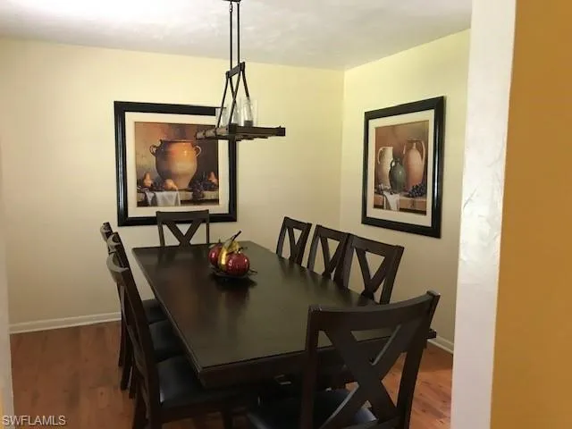 Dining area featuring dark wood-style flooring and baseboards
