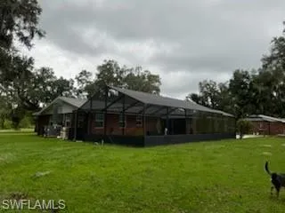 Rear view of property featuring a lanai and a lawn