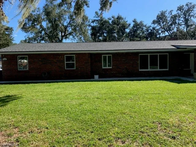 Back of property with brick siding and a yard
