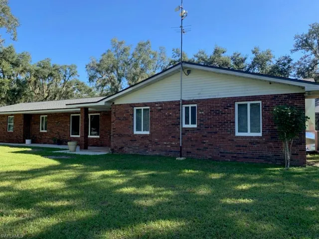 Back of house featuring brick siding, a patio, and a yard