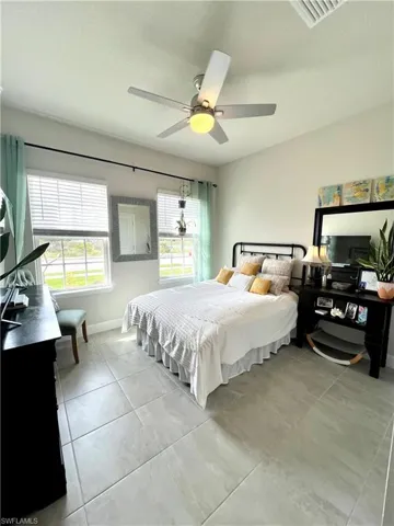 Bedroom featuring light tile patterned floors, a ceiling fan, and baseboards