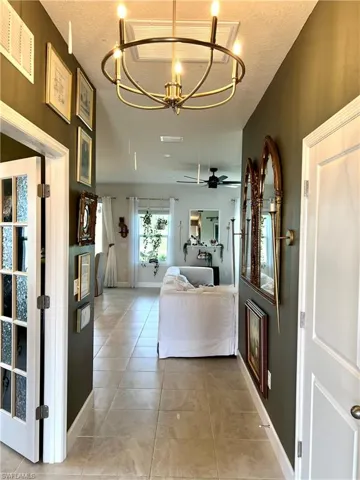 Den hallway featuring French doors, a chandelier, light tile patterned floors, and a textured ceiling.