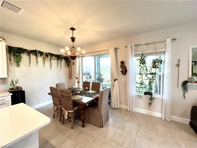 Dining space featuring a chandelier, baseboards, light tile patterned floors, and a textured ceiling