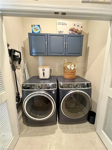 Laundry large closet with cabinet space, separate extra capacity washer and dryer, and tile floors