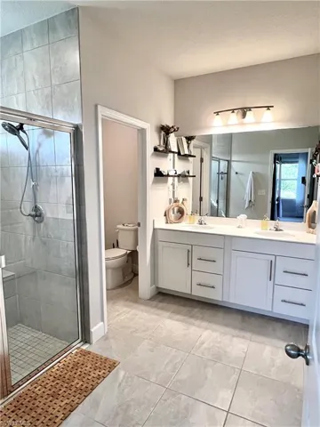 Bathroom with a stall shower, double vanity, and built-in bench in shower. Linen closet conveniently inside this space.