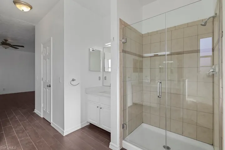 Bathroom featuring a shower stall, wood finish floors, and vanity
