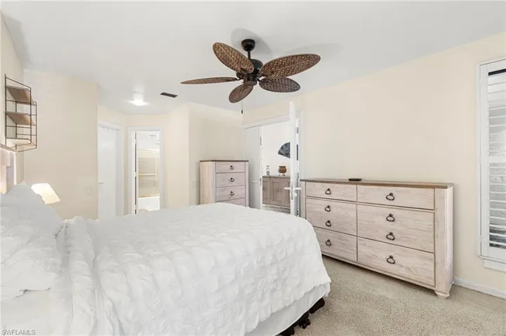 Bedroom with ensuite bath, a ceiling fan, and light carpet
