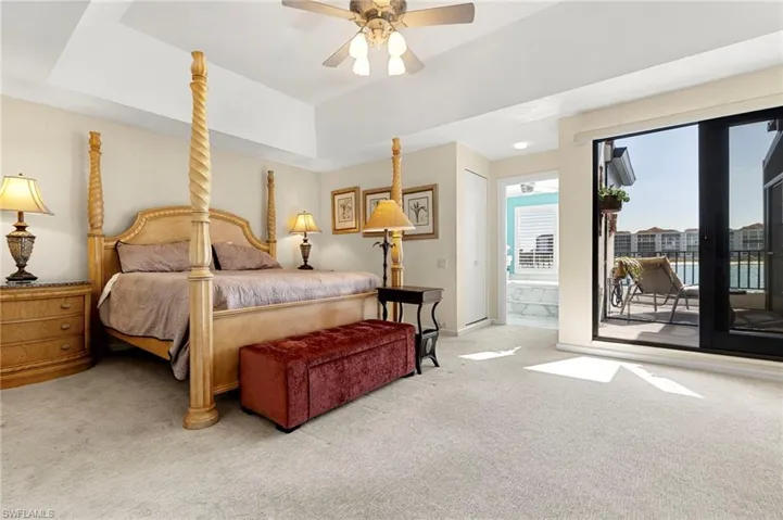 Carpeted bedroom featuring access to exterior, a tray ceiling, and ceiling fan