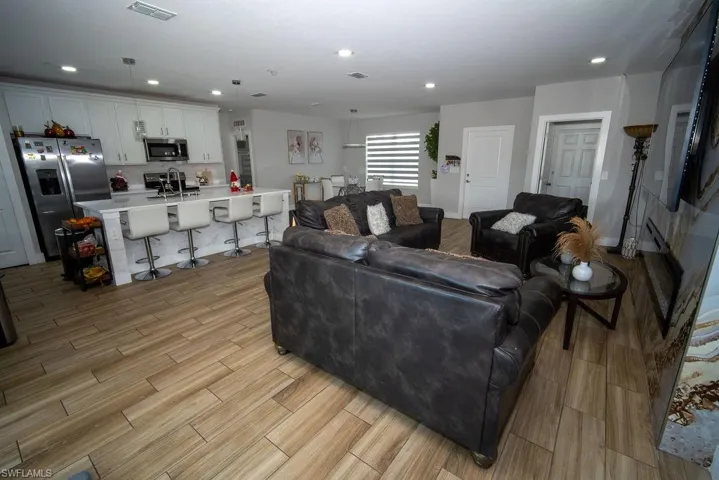 Living room with light wood-style flooring and recessed lighting