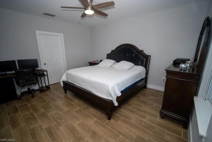 Bedroom featuring wood tiled floors, an office area, and a ceiling fan
