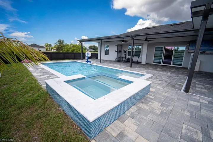 View of pool featuring a patio area, a pool with connected hot tub, ceiling fan, and a fenced backyard