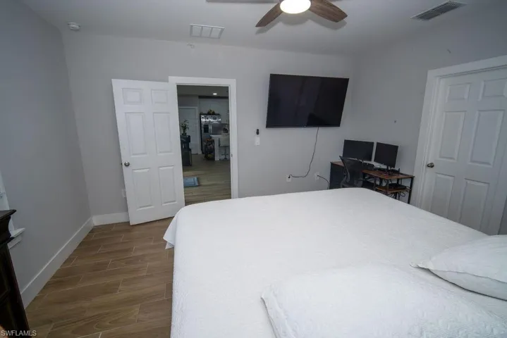 Bedroom with wood tiled floors, an office area, and ceiling fan