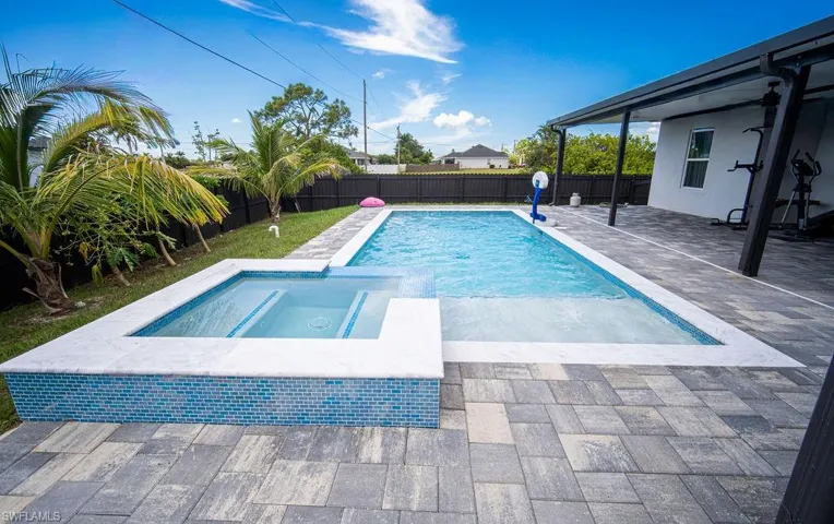 View of swimming pool featuring a patio, a pool with connected hot tub, and a fenced backyard