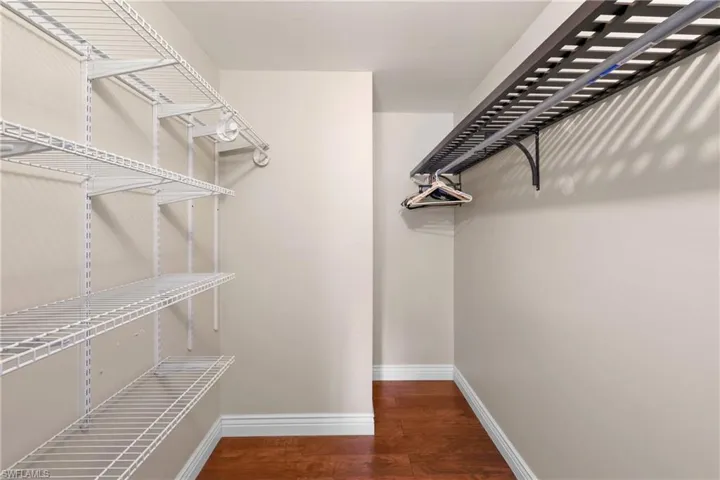 Master bedroom Walk in closet with dark hardwood / wood-style flooring