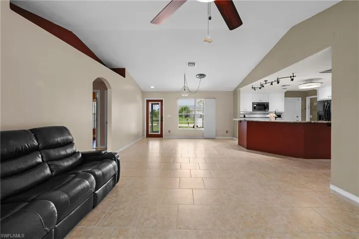 Living room featuring ceiling fan, vaulted ceiling and light tile floors