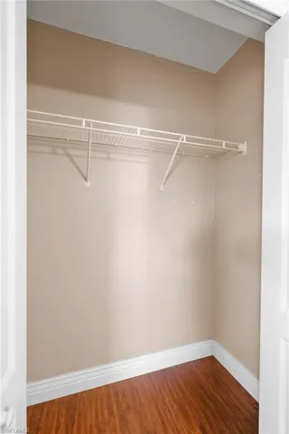 Walk in closet with hardwood / wood-style flooring