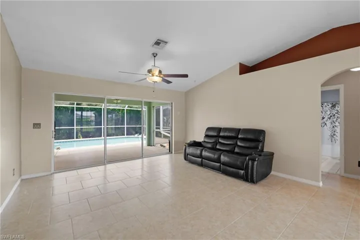 Tiled living room with vaulted ceiling and ceiling fan