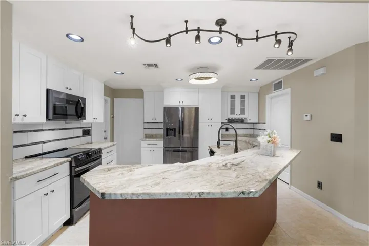 Kitchen with white cabinets, light tile floors, appliances with stainless steel finishes, and backsplash