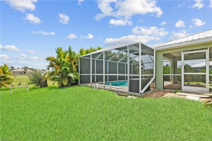 View of yard featuring a raised pool cage and side door