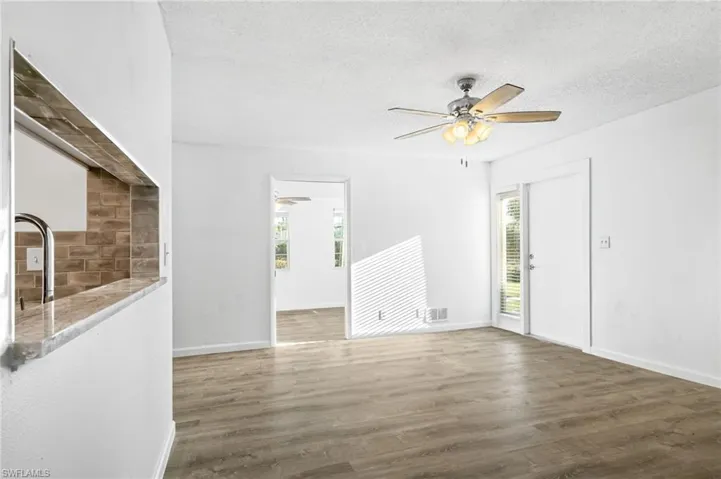 Empty room featuring a healthy amount of sunlight, a textured ceiling, and ceiling fan
