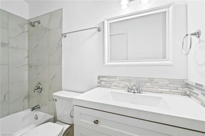 Full bathroom featuring vanity, tiled shower / bath combo, tasteful backsplash, and toilet. Second Floor.